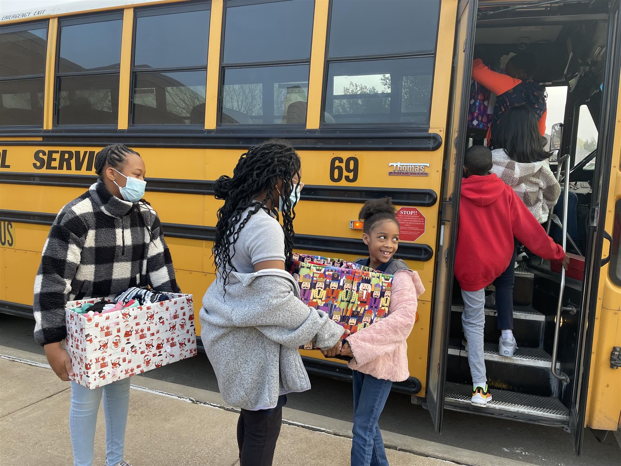 Students giving items to House of Hope in front of a school bus